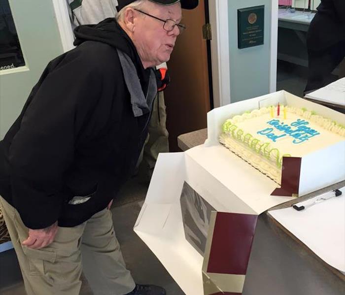 male employee blowing out candles on a birthday cake